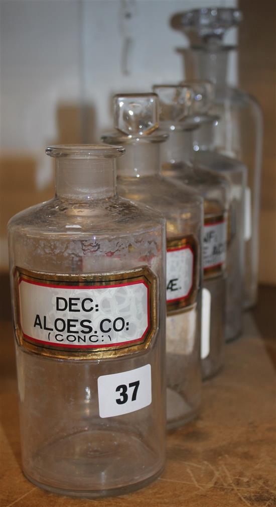 Set of four labelled glass apothecary jars and stoppers & a similar larger jar